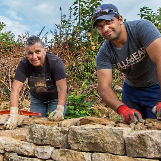 Une femme et un homme construisent ensemble un mur en pierre