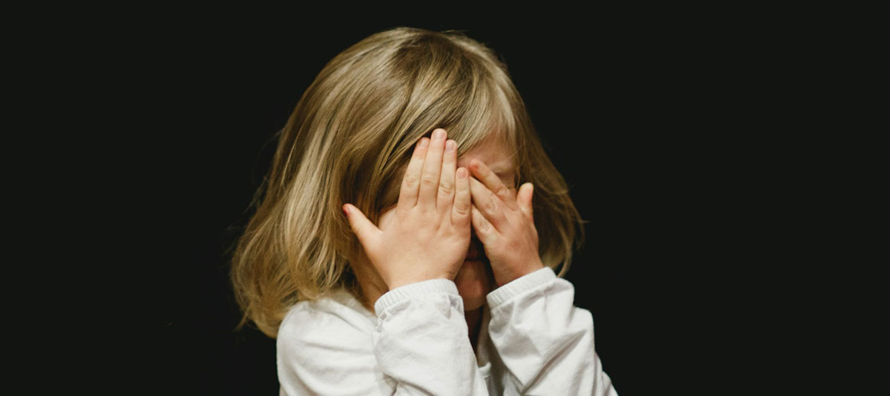 Enfant qui se cache les yeux sur font noir