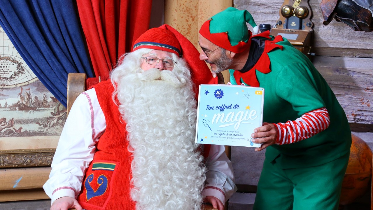 le père Noël avec un lutin à ses côtés qui tient une boite Magie à l'hôpital