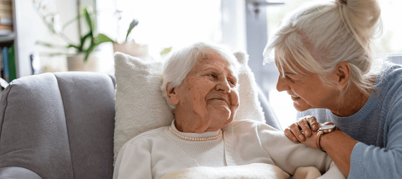 femme âgée sur un lit avec son aidante qui l'écoute