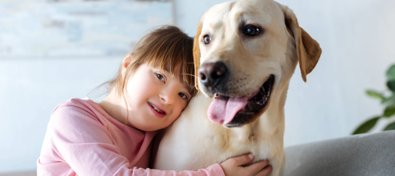 enfant trisomique qui fait un câlin à un handi'chien