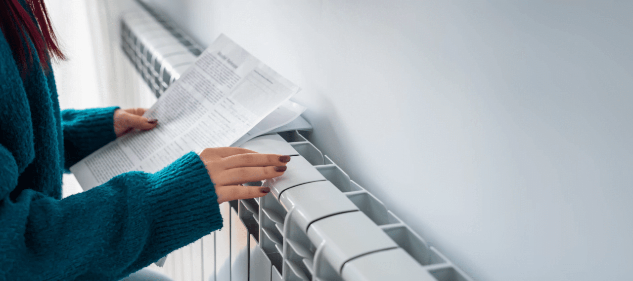 femme avec les mains posées sur un radiateur récent avec une facture