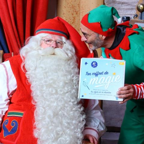le père Noël avec un lutin à ses côtés qui tient une boite Magie à l'hôpital