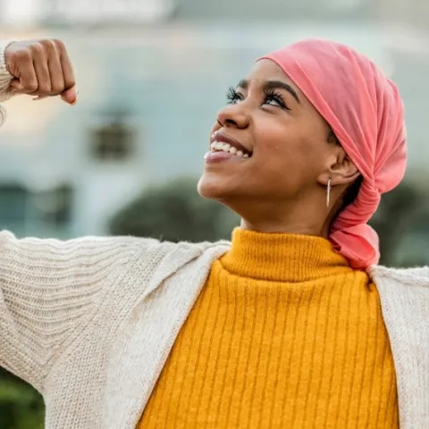 femme avec un foulard sur la tête les bras en l'air